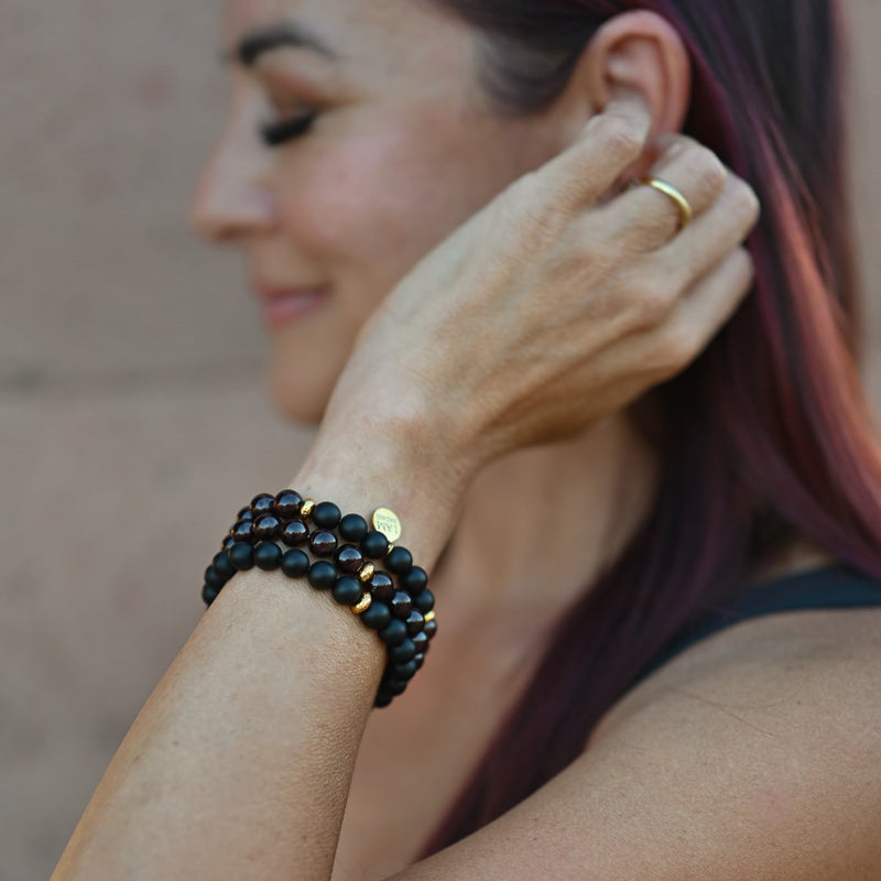 woman holding her hand to her hair, smiling authentically and wearing the everlur badass bracelet as a symbol of personal empowerment and authenticity