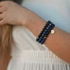 woman wearing the believe bracelet on her wrist and touching her hair