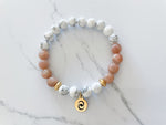 confidence bracelet with peach moonstone and howlite and everlur's infinite possibility gold charm